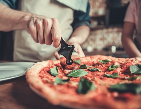 a man cutting a freshly baked pizza