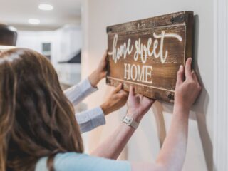 Couple hanging wooden “home sweet home” sign on a wall