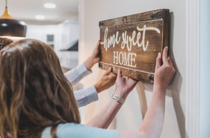 Couple hanging wooden “home sweet home” sign on a wall