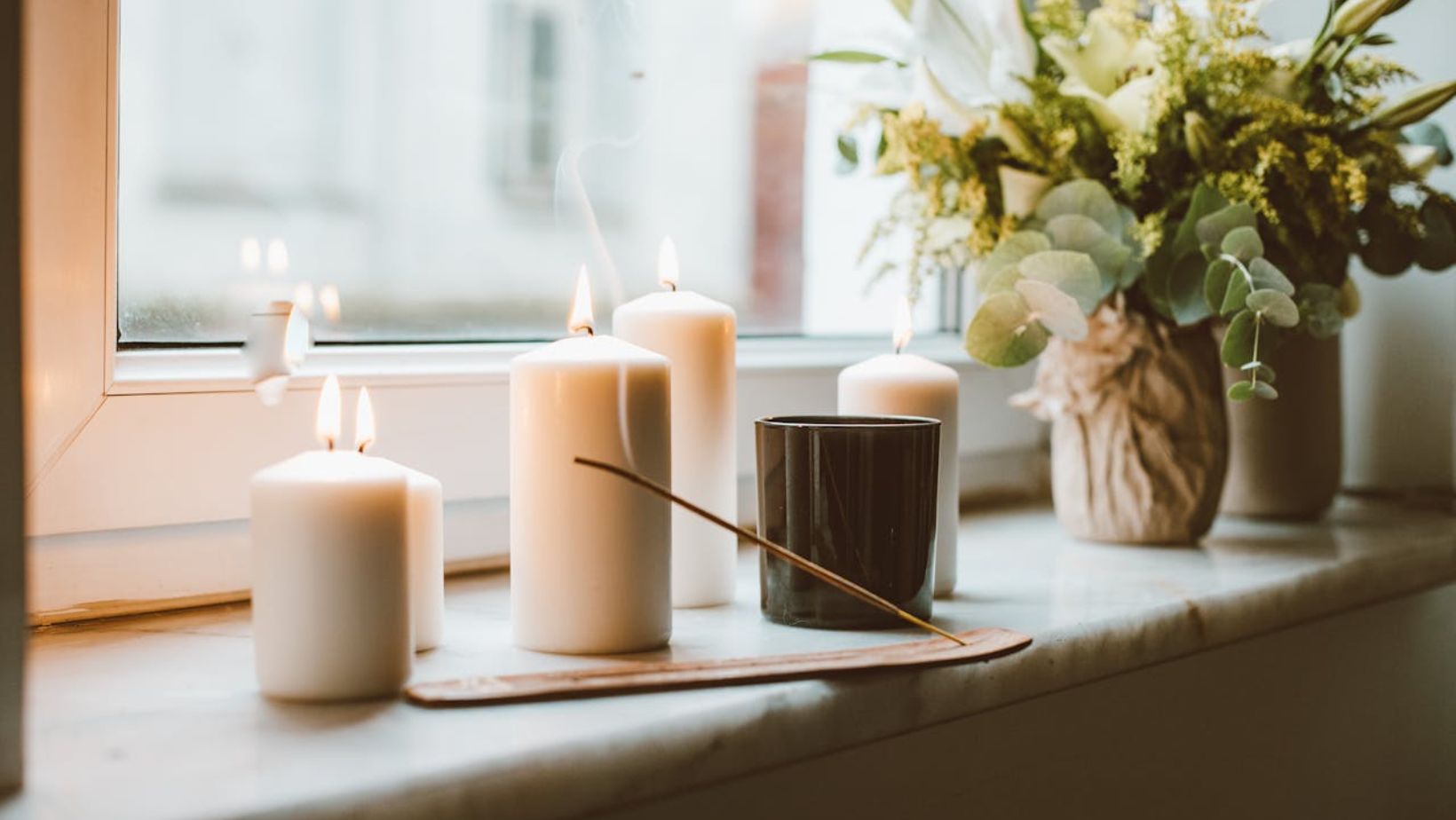 Lit candles, incense, plants on a windowsill