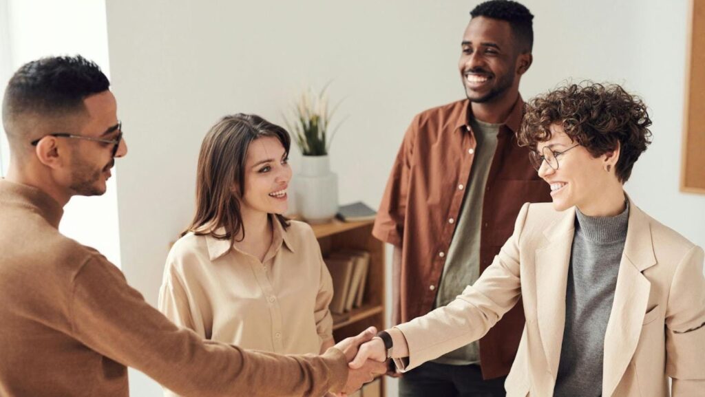 Smiling colleagues greeting with handshake.