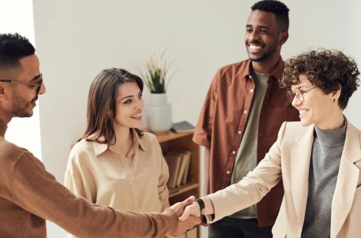 Smiling colleagues greeting with handshake.