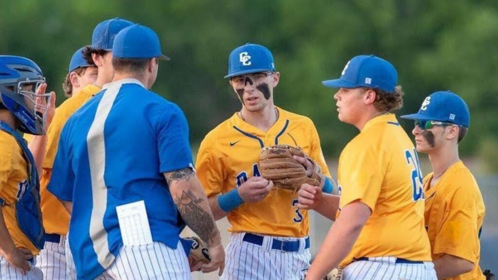 Baseball team huddles in yellow uniforms.