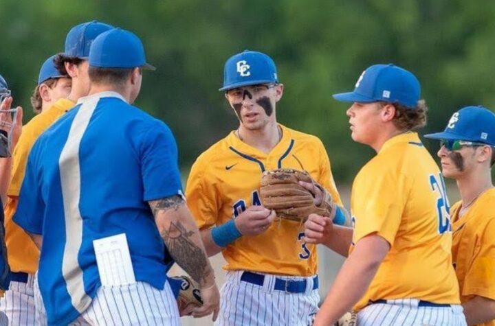Baseball team huddles in yellow uniforms.
