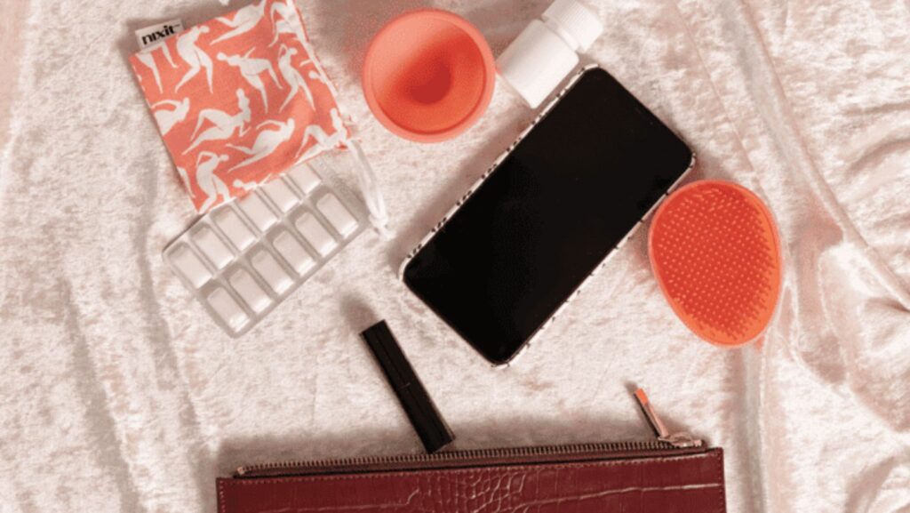 Purse essentials: phone, pills, mask, cup.