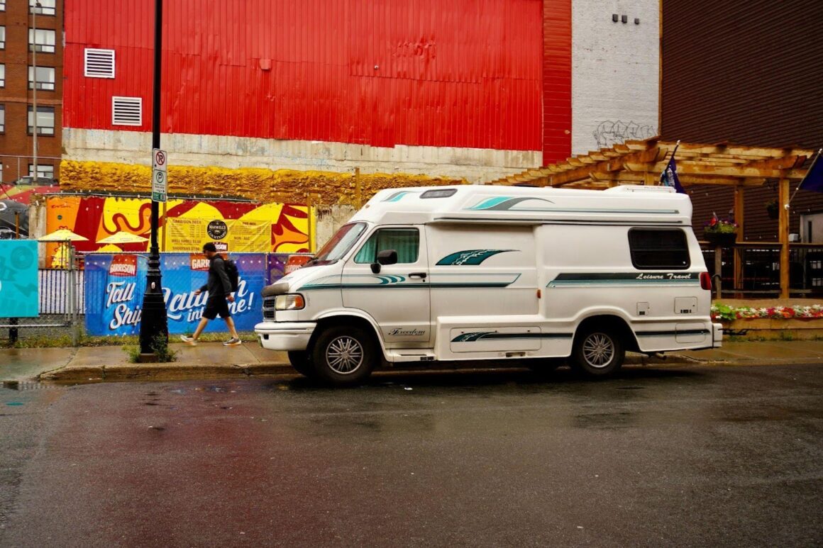 Camper van parked on rainy street.