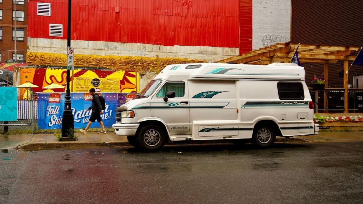 Camper van parked on rainy street.