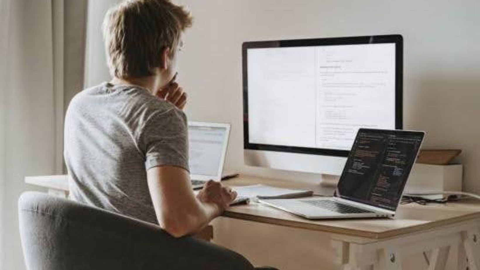Developer coding at multi-screen workstation.